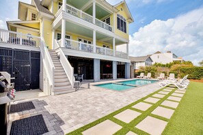 A two-story house with a pool, outdoor seating, and a well-maintained lawn.