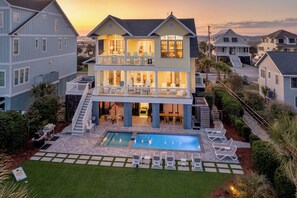 Une maison à deux étages dotée d’une piscine, d’un espace salon extérieur et d’un escalier menant à l’étage supérieur.