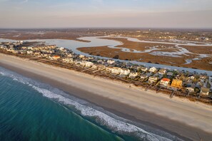 Vue aérienne d’une ville côtière avec des propriétés situées en bord de mer, une rivière et une plage.