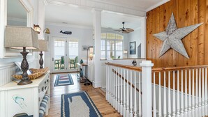 A spacious hallway with a wooden star decoration, a white railing, and a view to the outside. - Palmettos & Sunshine: Oceanfront w/ Pool, Hot Tub, & Stunning Views (Garden City Beach)