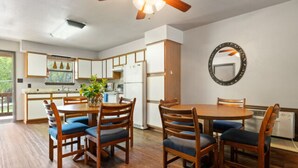 Une cuisine moderne avec des meubles en bois, une table à manger avec des chaises et un ventilateur de plafond.