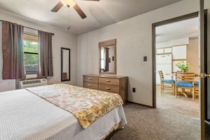 Un dormitorio con cama, cómoda, espejo y una puerta que da a un comedor.