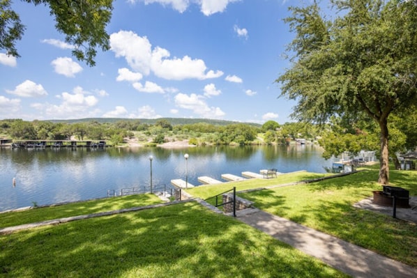 Un parque junto al río con sendero para caminar, bancos y un muelle.