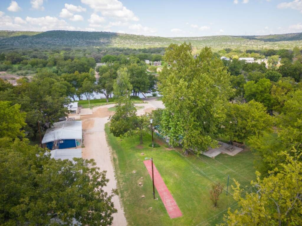 An aerial view of a property with a red pathway, green lawns, and scattered trees.