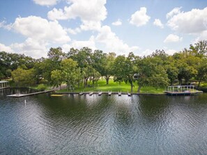 A calm lake with a dock and a boat, surrounded by lush green trees and a clear sky.