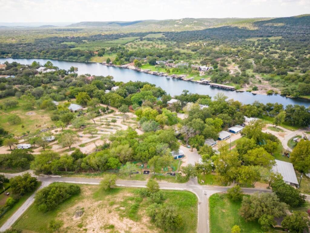 Vue aérienne d’une zone rurale avec une rivière, des maisons dispersées et une végétation luxuriante.