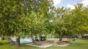 A park with picnic tables, a playground, and a swimming pool. - RV Site - Pull Through 25 (Burnet)