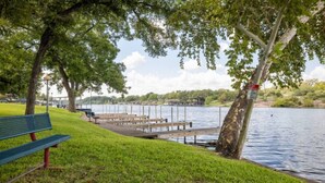 A lakeside park with a bench, wooden docks, and a grassy area. - RV Site - Pull Through 25 (Burnet)