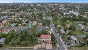 Una vista aerea di una zona residenziale con case, strade e un ampio complesso industriale sullo sfondo.