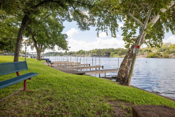 A lakeside park with a bench, wooden docks, and a grassy area.