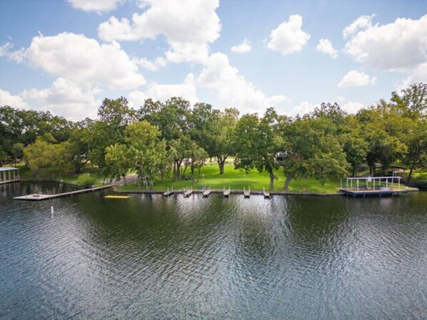 A calm lake with a dock and a boat, surrounded by lush green trees and a clear sky.