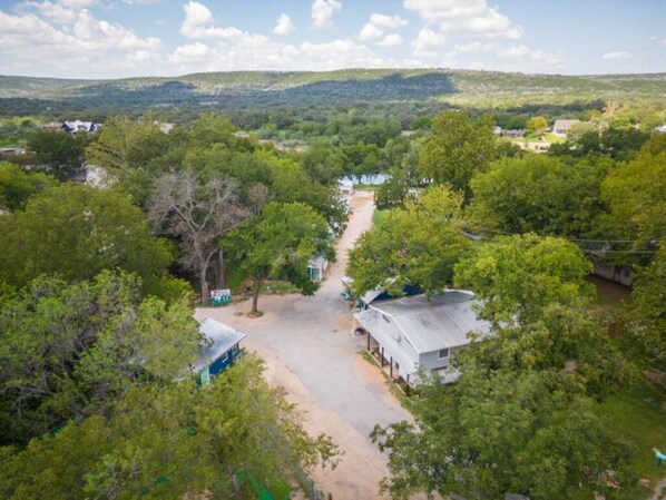 An aerial view of a rural area with scattered houses, a dirt road, and dense greenery. - RV Site - Pull Through 43 (Burnet)