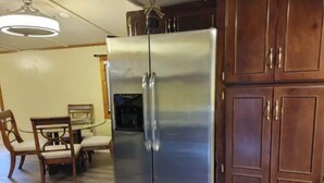 Eine Küche mit Edelstahlkühlschrank, Holzschränken und einem Esstisch mit Stühlen.