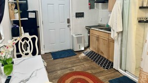 Cocina compacta con puerta blanca, muebles de madera, estufa integrada y una pequeña encimera.