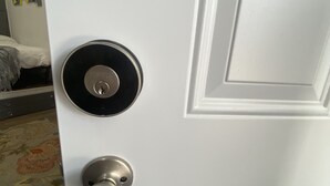 Una puerta blanca con un ojo de cerradura y un llamador metálico redondo.