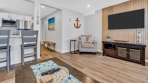 Un salon moderne avec un téléviseur, un canapé et un coin repas avec des chaises.