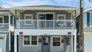 Un immeuble résidentiel de deux étages doté d’un balcon, d’un garage et d’un panneau indiquant « Stationnement interdit ».