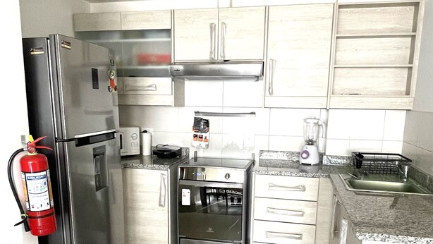 A modern kitchen with stainless steel appliances, a built-in oven, and a coffee maker. - New, comfortable and very well equipped apartment. (Quito)