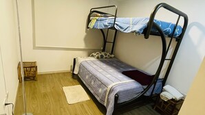 A small, single-bedded room with a bunk bed, a standing lamp, a wooden floor, and a small stool. - New, comfortable and very well equipped apartment. (Quito)