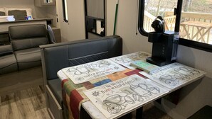 A cozy RV interior with a dining area, a coffee station, and a view of the outdoors.