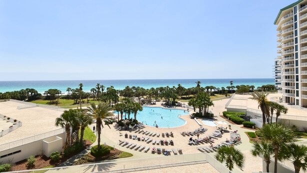 Un resort con piscina central, áreas de descanso y vista al océano.