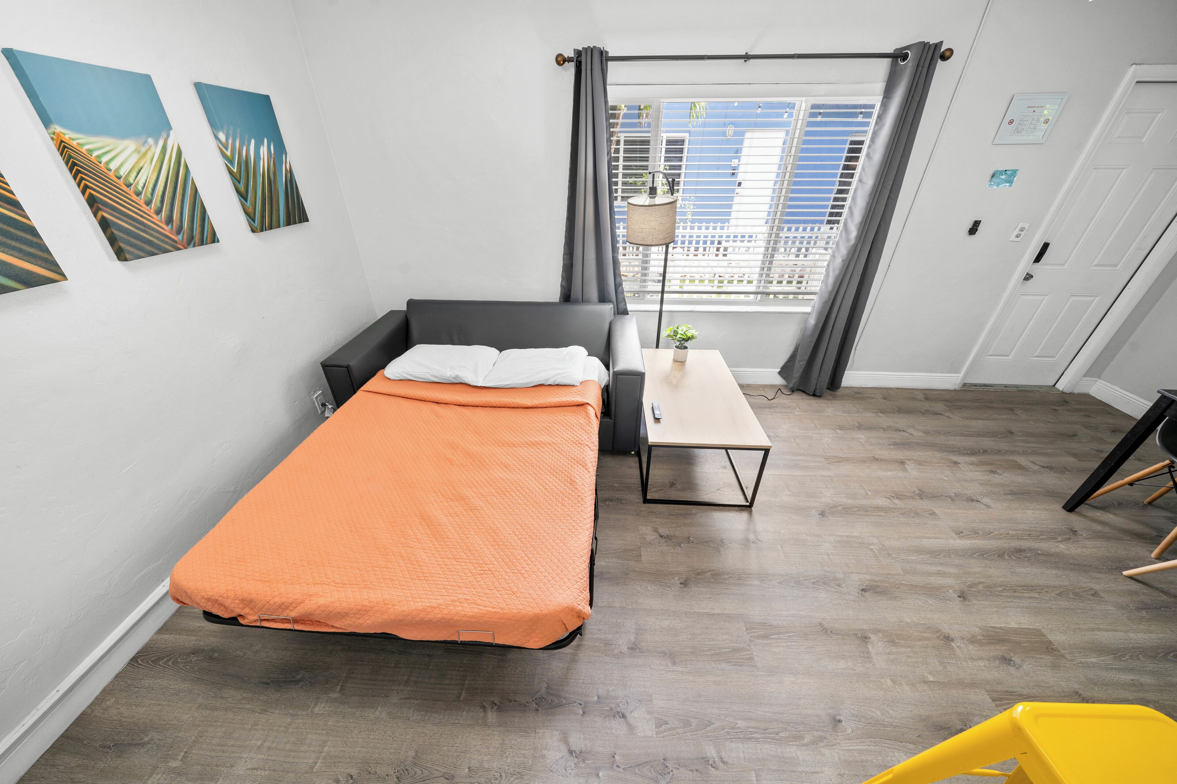 A bedroom with a bed, a small table, a chair, and a window with curtains.