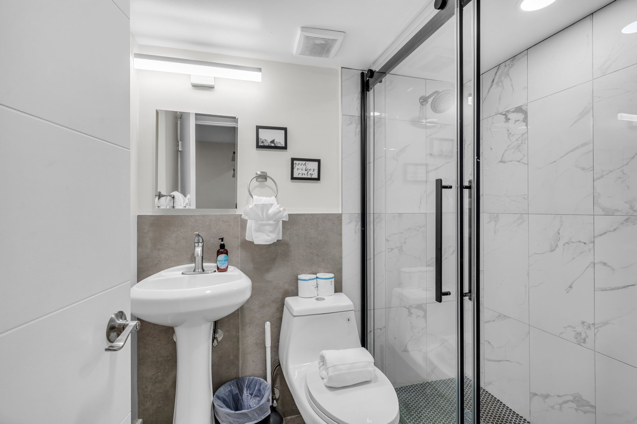 Een moderne badkamer met een wastafel, toilet en douchecabine van glas.