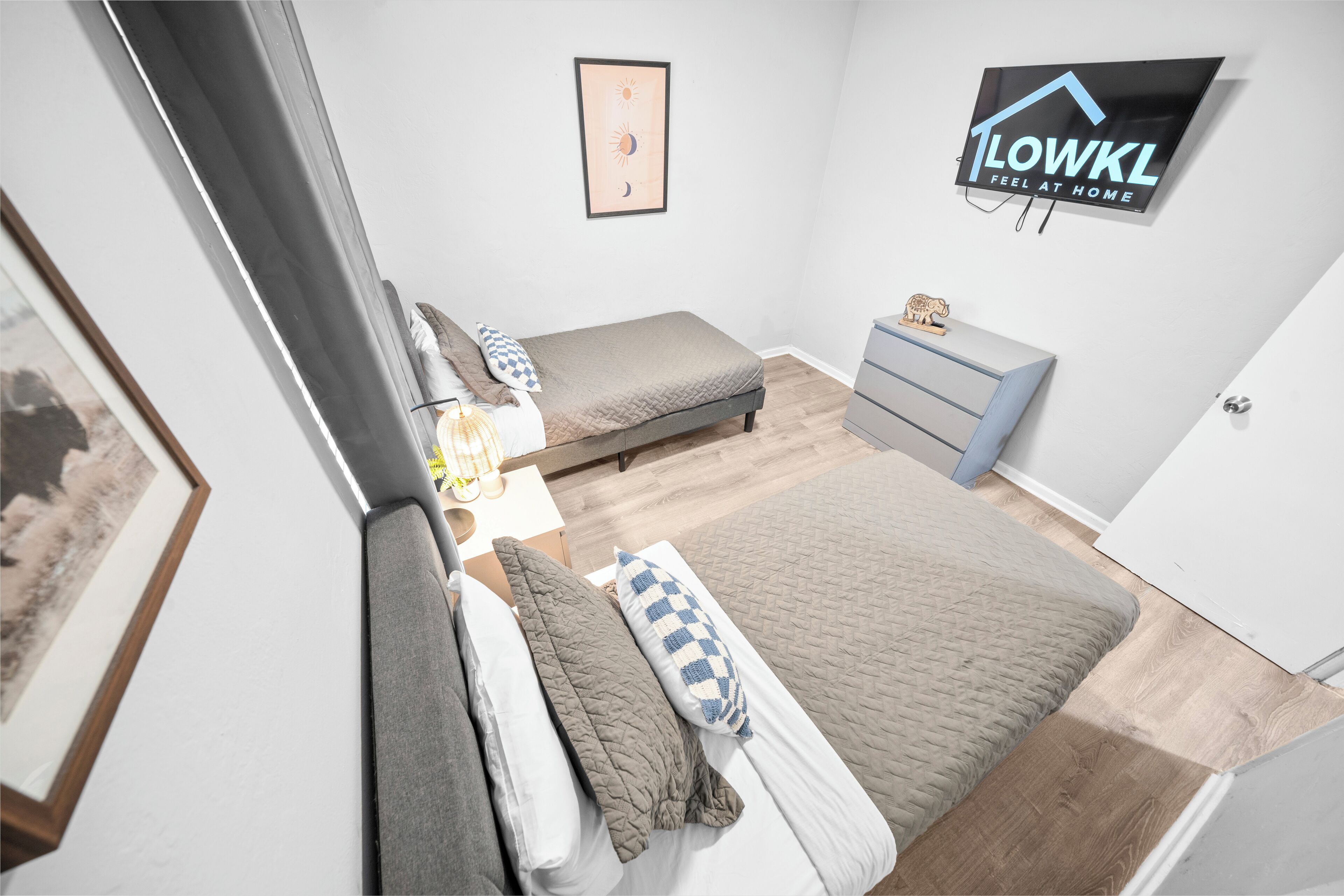 Un dormitorio con cama, mesitas de noche, cómoda y un cuadro enmarcado en la pared.