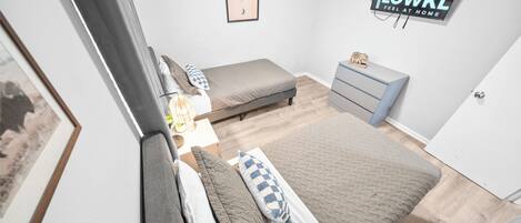 Un dormitorio con cama, mesitas de noche, cómoda y un cuadro enmarcado en la pared.