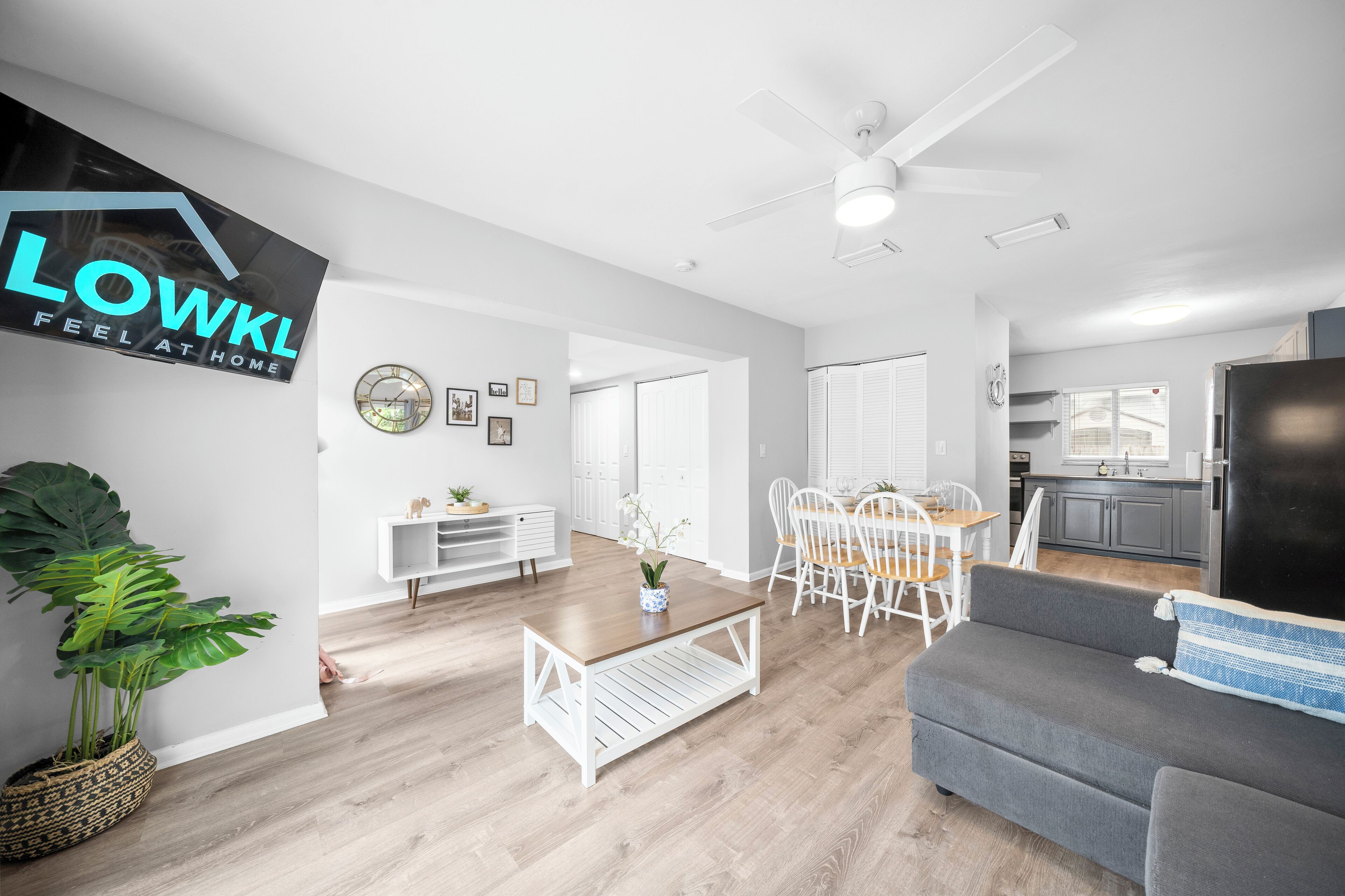 A spacious living area with a dining table, a gray sofa, and a ceiling fan.