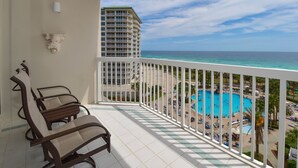 Un balcone con vista su una piscina e una spiaggia, una sedia e un edificio sullo sfondo.