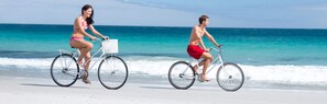 Two people riding bicycles on a beach with the ocean in the background. - Beautiful 8th Floor Beach Views at Destin's Silver Shells! (Destin)
