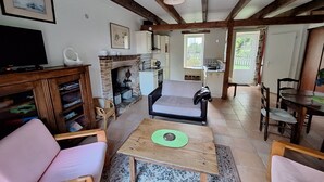 Een gezellige woonkamer met een open haard, een televisie en een eethoek met een tafel en stoelen.