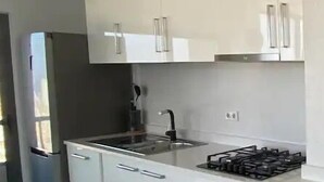 Una cocina moderna con armarios blancos, electrodomésticos de acero inoxidable y una encimera negra.