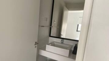 Un baño moderno con lavamanos, espejo y toallero blancos.