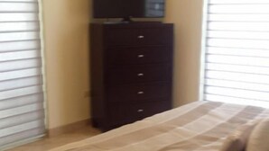 Un dormitorio con cama, cómoda y televisor encima.