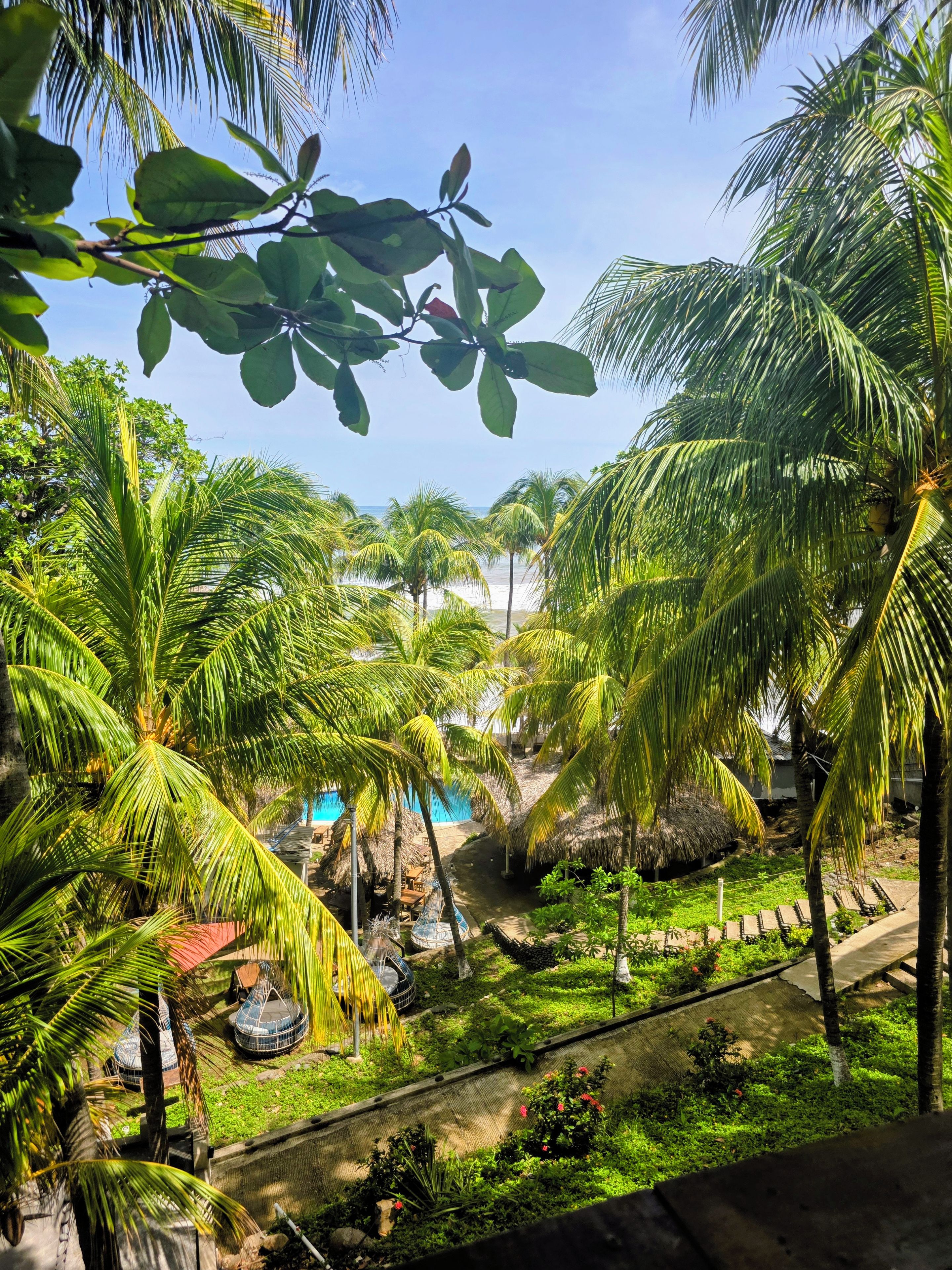 Ein tropisches Resort mit Palmen, einem Swimmingpool und einem strohgedeckten Gebäude.