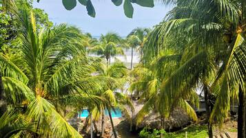 Ein tropisches Resort mit Palmen, einem Swimmingpool und einem strohgedeckten Gebäude.