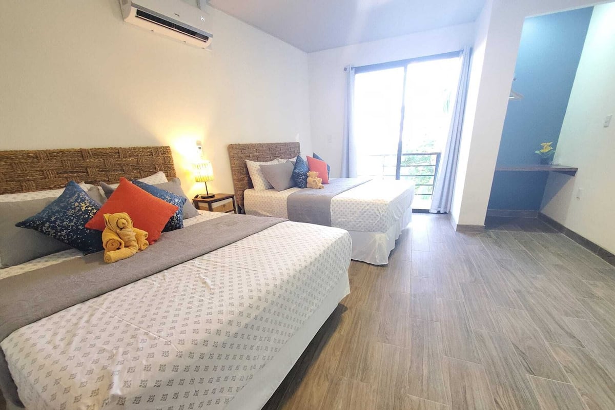 A hotel room with two beds, a large window, and a wooden floor.