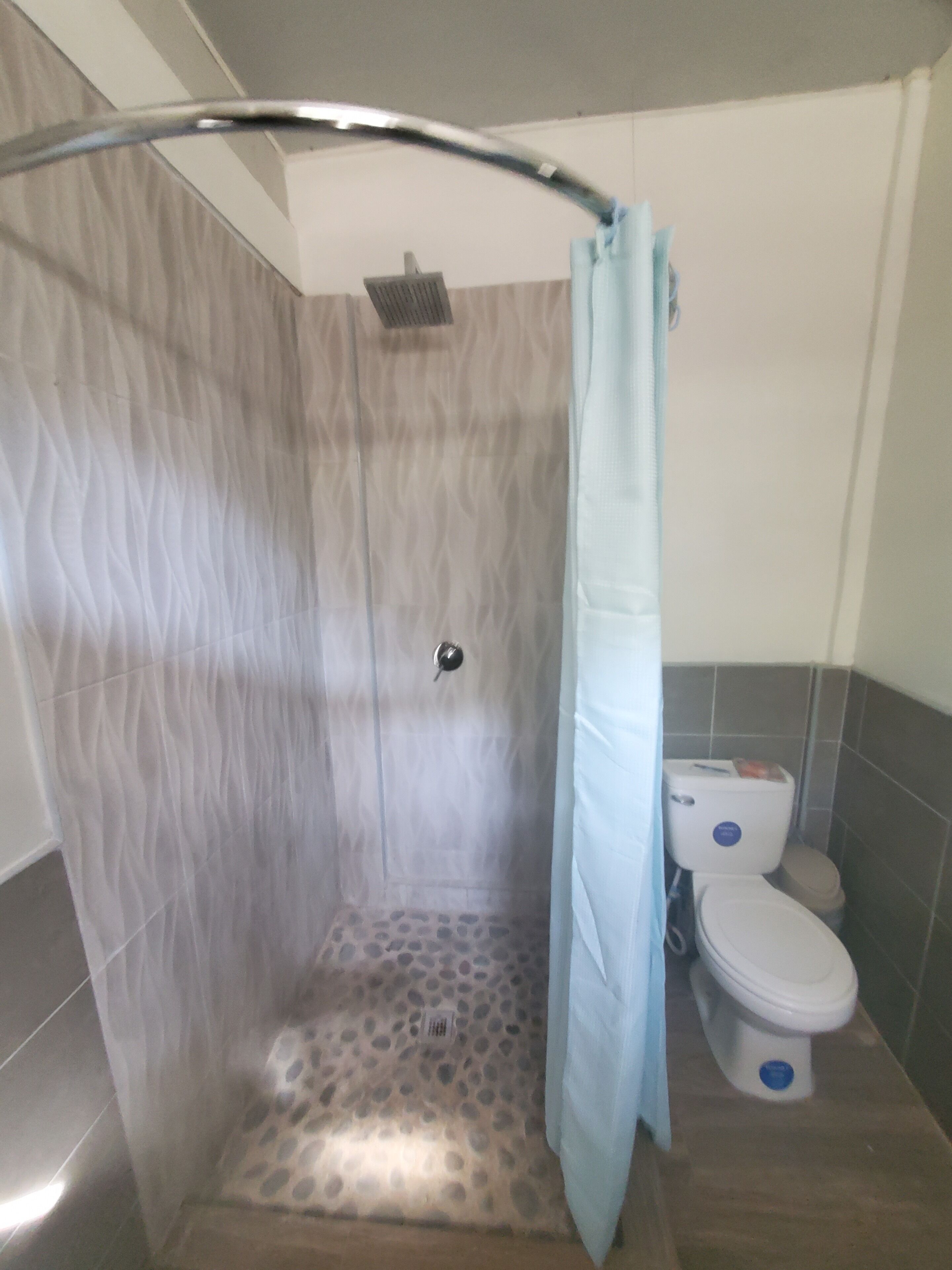 Ein Badezimmer mit Duschkabine, Toilette und Fliesenboden.