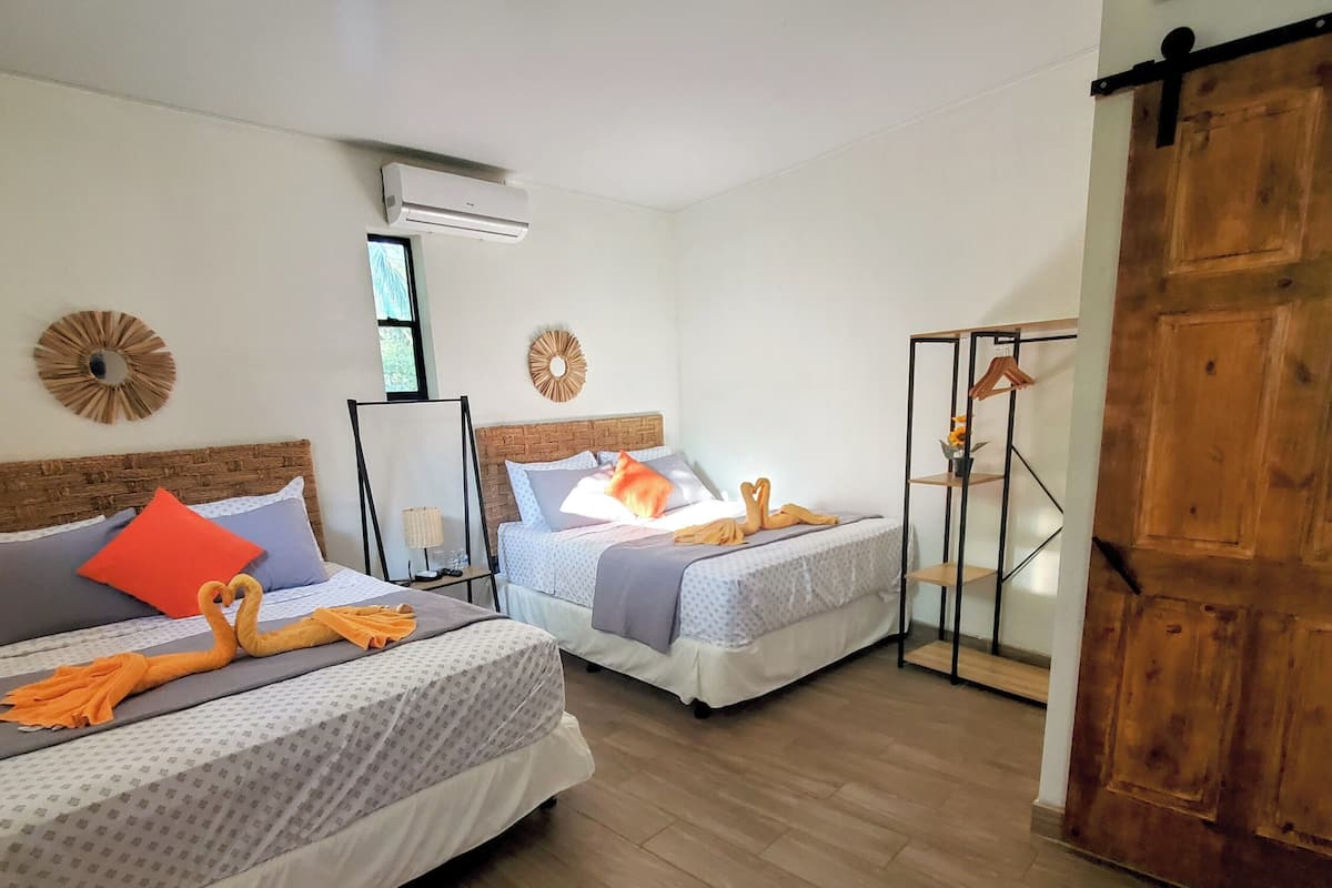A hotel room with two beds, a wooden door, and a mirror.