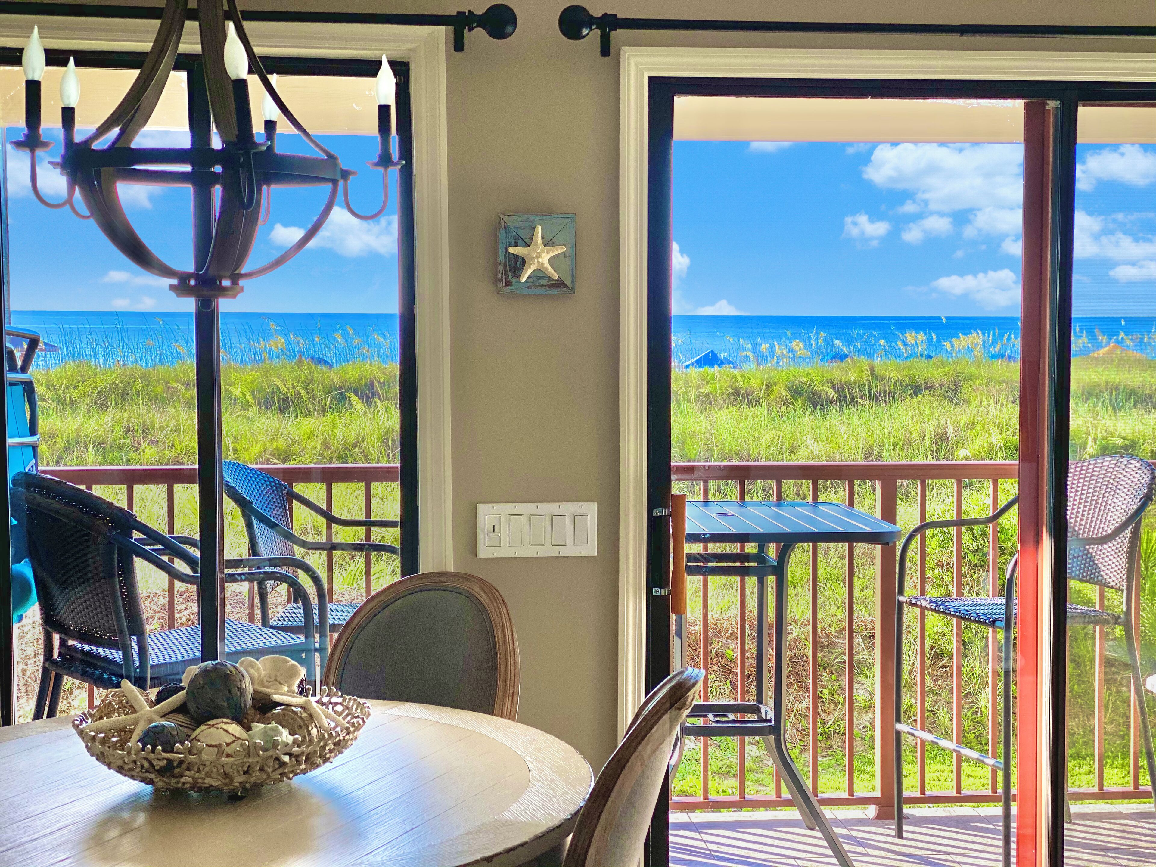 Quarto com vista para o oceano, um candelabro, decoração com estrela-do-mar e uma mesa com uma cesta de objetos.