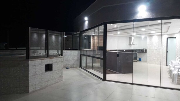 En moderne bygning med en glasfacade, et synligt køkkenområde gennem glasset og et flisegulv.