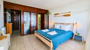 A bedroom with a bed, a nightstand, a wooden headboard, and a view of the outside. - FLH Portimão Bright Studio with Balcony (Portimão)