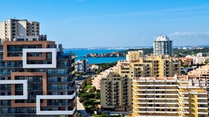A high-rise building with multiple balconies, a clear view of the coastline, and a distant cityscape. - FLH Portimão Bright Studio with Balcony (Portimão)