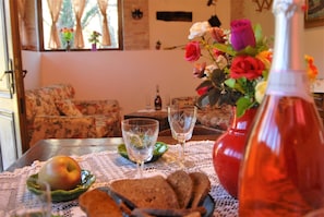 A dining table with a lace tablecloth, a bottle, glasses, and a plate with an apple and bread.