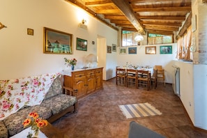 A cozy living room with a sofa, wooden cabinet, and dining area with chairs and a table.
