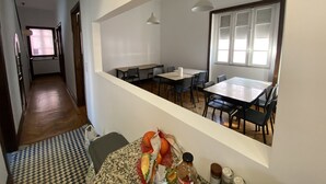 Un comedor con techo alto, un ventanal con persianas y vista al pasillo.
