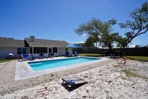 Ein Garten mit Swimmingpool, Liegestühlen und einer überdachten Terrasse.