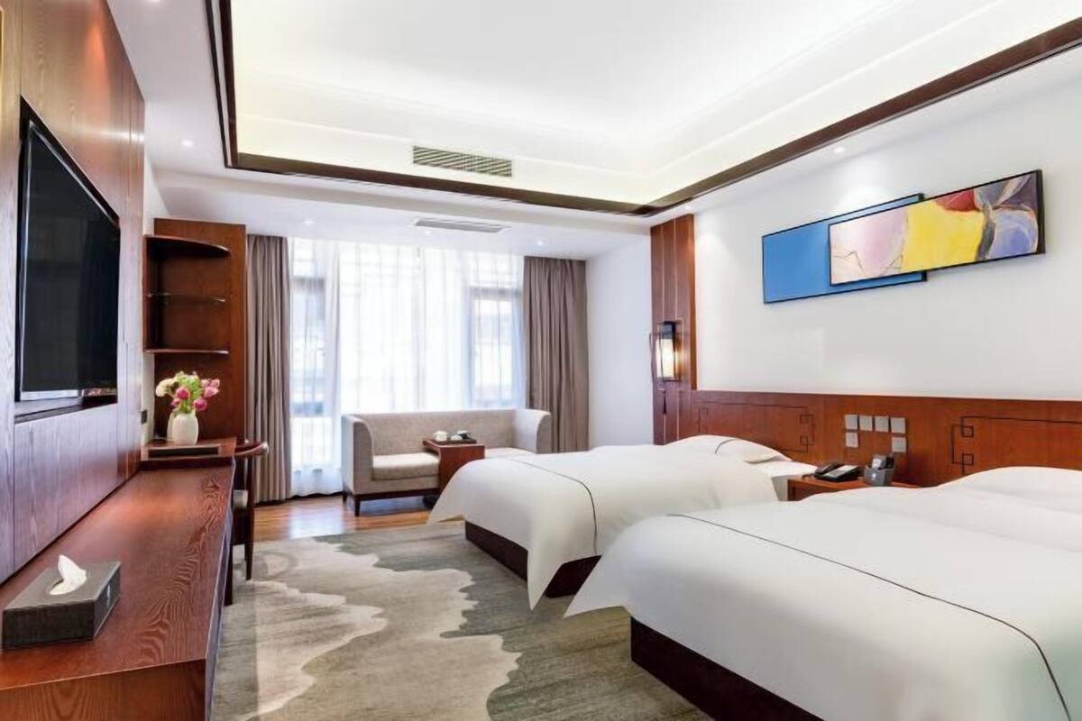Habitación de hotel con dos camas, televisión, escritorio y silla.